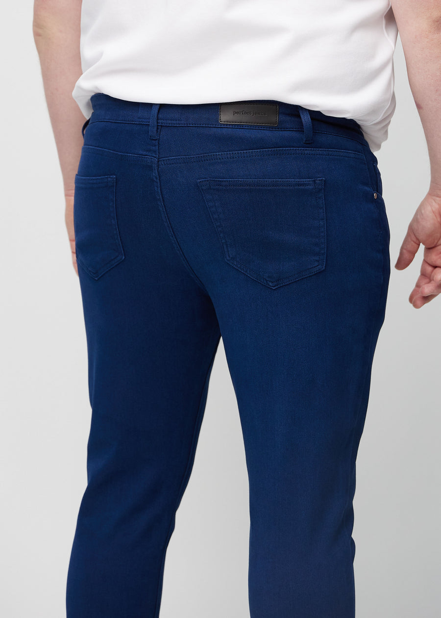 Close-up back view of dark blue slim jeans on a plus-size model showing details.