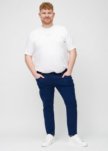Full-length view of a plus-size model in dark blue slim jeans.