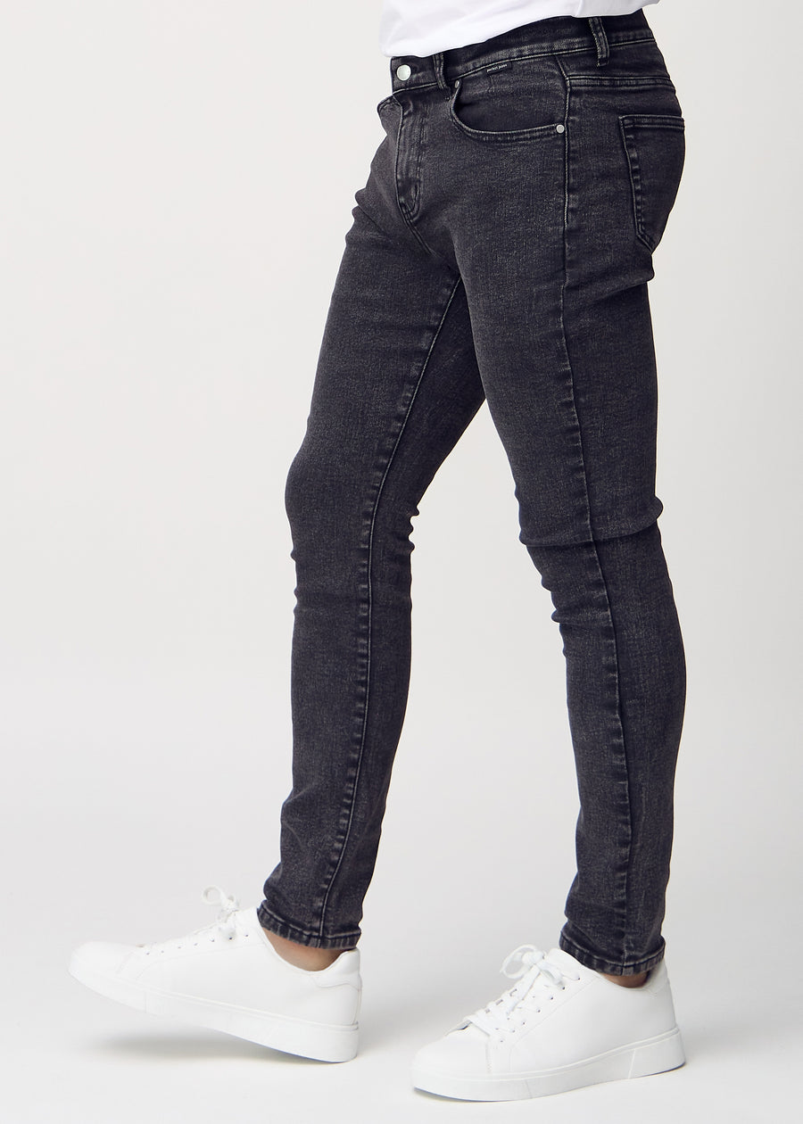Dark grey denim slim jeans viewed from the side on a model.