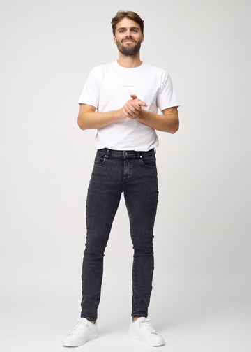 Full-length view of a model in dark grey denim slim jeans.