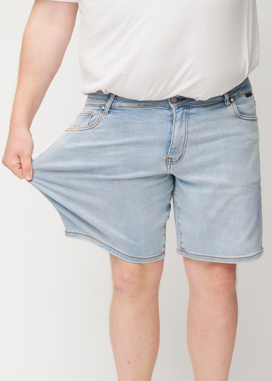 The plus-size model stretches the light blue denim shorts for men in the colour Waves at the thigh to show the material&
