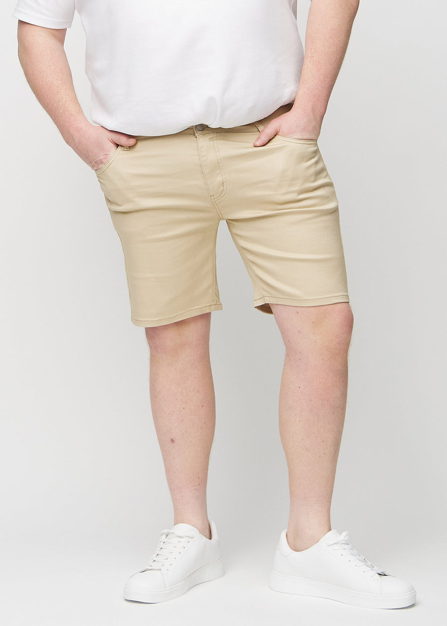 Beige middle-slim shorts, which fit straight along the thigh and end just above the knee on a plus-size model, seen from the front.