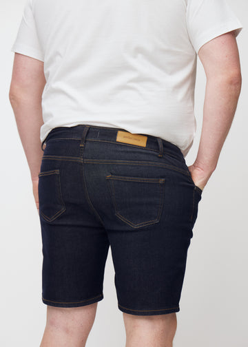 Deep dark blue denim shorts for men in the colour Midnights seen from the back in close-up on a plus-size model.
