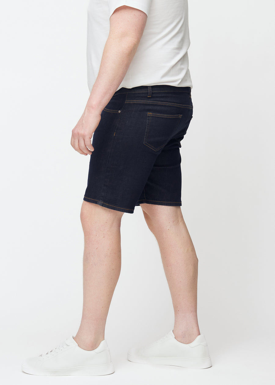 Deep dark blue denim shorts for men in the colour Midnights with a slim fit seen from the side on a plus-size model.
