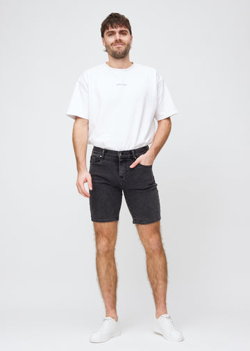 Full image of a model in dark grey denim middle-slim shorts.