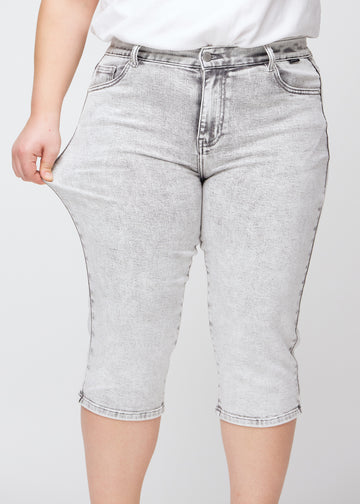 Plus-size model strækker caprisene ved låret for at vise stretch.