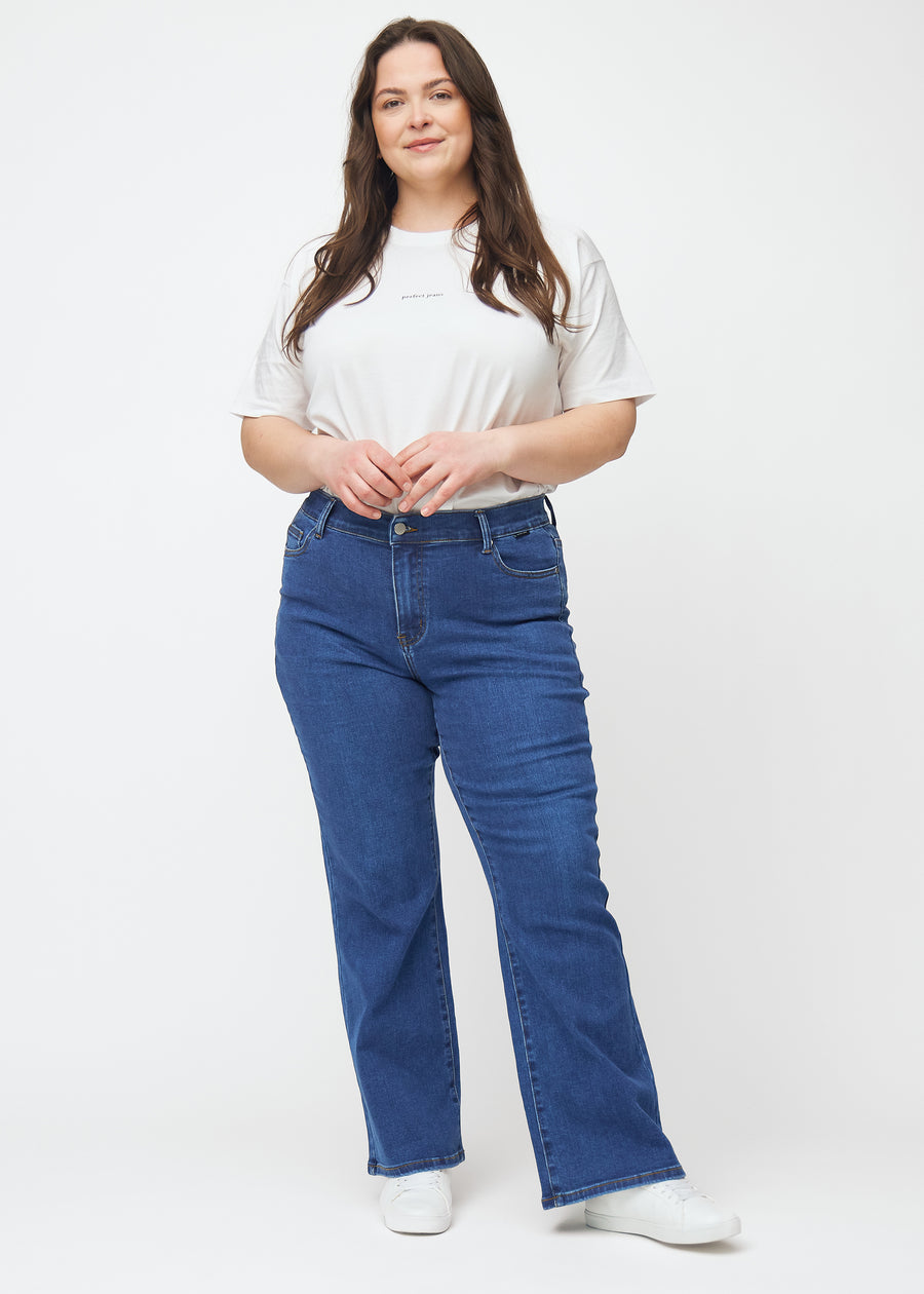 Plus-size model går ind i billedet, strækker i jeansene, viser dem frem ved at dreje rundt og forlader derefter billedet.