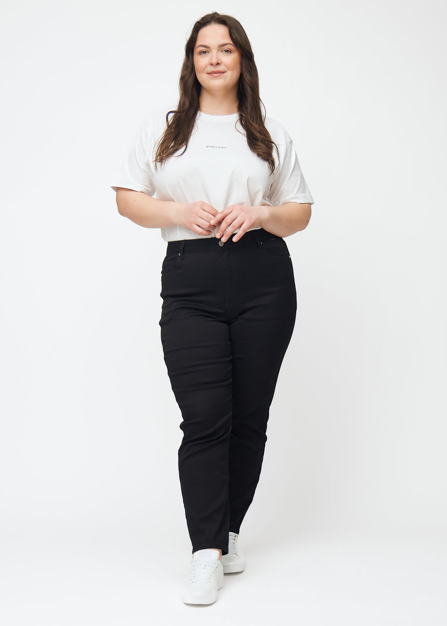 Plus-size model går ind i billedet, strækker i jeansene, viser dem frem ved at dreje rundt, og forlader derefter billedet.