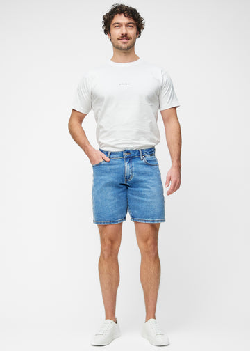 Model viser blå denim shorts til mænd i farven Rivers med regular pasform i bevægelse.