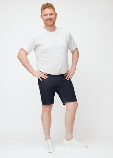 Plus-size model viser dyb mørkeblå denim shorts til mænd i farven Midnights med slim pasform i bevægelse.