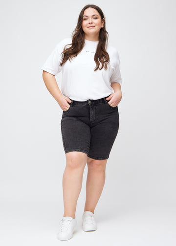 Plus-size model går ind i billedet, strækker i sine shorts, viser dem frem ved at dreje rundt, og forlader derefter billedet.